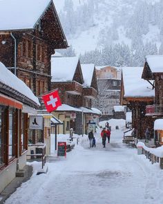 people walking down a snow covered street in the mountains