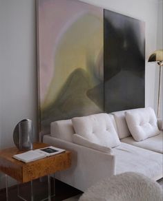 a living room with white furniture and a large painting on the wall above it's couch