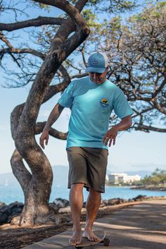 a man riding a skateboard down a sidewalk next to a tree lined beach area