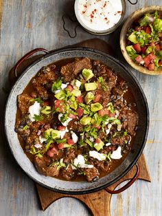 a bowl filled with meat and vegetables on top of a wooden table