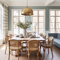 a dining room table with chairs and a bench in front of large windows that look out onto the woods