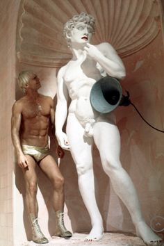 two men standing next to each other in front of a white statue with a megaphone