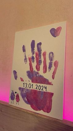 a handprint is displayed on a wall with pink lighting behind it and the date written in black