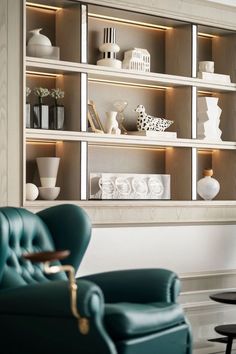 a blue chair sitting in front of a book shelf filled with vases and other items