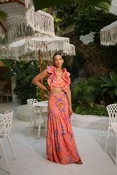 PRE-SALE DESCRIPTION: This exquisite two-piece skirt set is a statement of bold elegance, featuring a vibrant coral color adorned with intricate paisley and floral patterns in shades of blue, pink, and green. The cropped top showcases voluminous ruffled sleeves and a fitted bodice, offering a dramatic yet feminine touch. Paired with a high-waisted, tiered maxi skirt that flows effortlessly with every movement, this set is perfect for a summer getaway or a stylish day out. The lightweight fabric Pink Tiered Skirt Set For Summer, Pink Long Skirt Set For Summer, Orange Two Piece, Tiered Maxi Skirt, Summer Getaway, Tropical Vacation, Ruffled Sleeves, Coral Color, Cropped Top