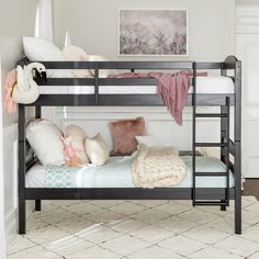 a black bunk bed with pillows and blankets on it in a white room next to a rug