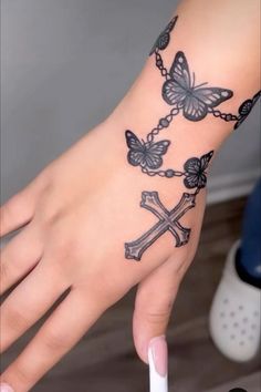 a woman's hand with a cross and butterflies tattoo on it