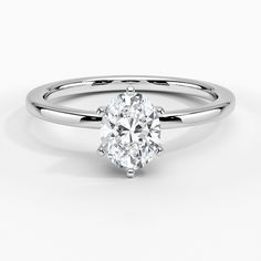 an oval cut diamond engagement ring on a white background