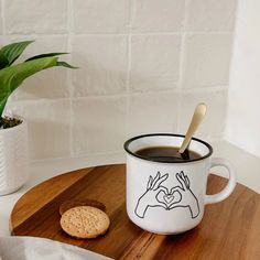 a cup of coffee with a spoon in it on a wooden tray next to a potted plant