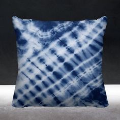 a blue and white tie - dyed pillow sitting on a gray surface with black background