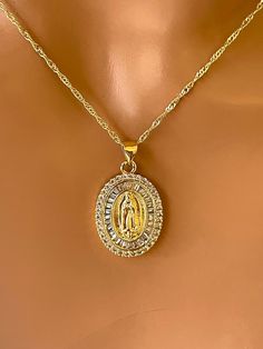 This is a beautiful 14 K gold filled Our lady Guadalupe pendant necklace. This beautiful charm features cubic zirconia surrounding Guadalupe image, measures 22 x 16 mm and hangs on a beautiful Singapore chain with lobster clasp and back. Chain length is 18 inches necklace is 14 K gold filled.  Comes in a cute gift box ready to present. This charm is spectacular super sparkly along with the Singapore chain, just stunning. Gold Virgin Mary Pendant Necklace, Gold Our Lady Of Guadalupe Pendant Necklace, Gold Virgin Mary Medallion Jewelry, Gold Our Lady Of Guadalupe Round Pendant Necklace, Gold Medallion Necklace With Our Lady Of Guadalupe, Gold Our Lady Of Guadalupe Medallion Necklace, Gold Medallion Necklace Of Our Lady Of Guadalupe, Yellow Gold Oval Necklace With Our Lady Of Guadalupe, Catholic Jewelry Necklace