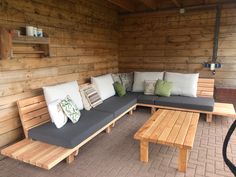 a wooden bench sitting on top of a patio next to a fire hydrant with pillows