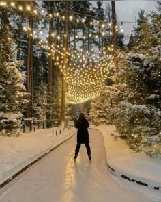 a person standing on a snow covered road with lights hanging from the ceiling above them