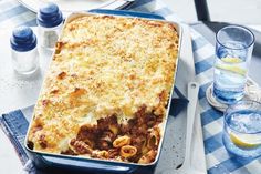 a casserole dish with meat and cheese on a blue checkered tablecloth