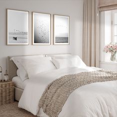 a bed with white sheets and pillows in a bedroom next to two pictures on the wall