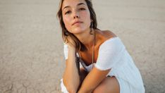 a woman is sitting on the ground with her head resting on her hand and looking off to the side