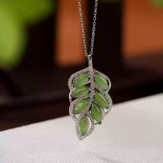 Jade Leaf Pendant Necklace (without chain) Material: S925 Sterling Silver with Gold PlatingGemstone: Jade (approximately 4mm x 7mm)Weight: Approximately 4.5gSize: Pendant Dimensions: 39mm x 18mm Description:Embrace the beauty of nature with this stunning Jade Leaf Pendant Necklace. Crafted in gold-plated S925 sterling silver, this pendant showcases a cluster of vibrant jade gemstones in an intricate leaf design. The soft green hues of the jade paired with a halo of sparkling accents create a fresh and elegant look, perfect for both everyday wear and special occasions. The pendant hangs gracefully from a delicate chain, adding a touch of refined sophistication to your style. Note: Each jade stone is natural, ensuring a unique character and beauty for every piece. The Beauty Of Nature, Pearl Jewelry Necklace, Natural Stones Necklace, Gold Statement Earrings, Green Hues, Natural Stone Jewelry, Natural Stone Bracelets, Delicate Chain, Anklet Bracelet