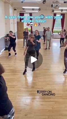 a group of people dancing in a large room with words on the wall above them