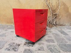 a red filing cabinet sitting on top of a stone floor