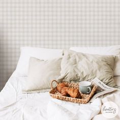 a basket with some croissants and a cup on top of the bed