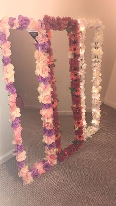 a mirror with flowers on it sitting in the middle of a carpeted floor next to a wall