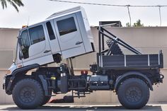 a white truck with a large metal structure on the back is parked in front of a building