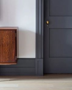 a wooden cabinet sitting in the corner of a room next to a door with a clock on it