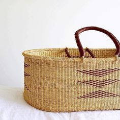 a woven basket sitting on top of a white bed next to a brown handlebar