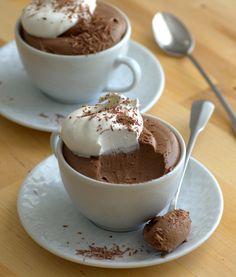 two white cups filled with chocolate pudding and whipped cream