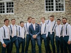 a group of men standing next to each other in front of a stone building with windows