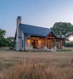 a small house in the middle of a field with tall grass and trees around it