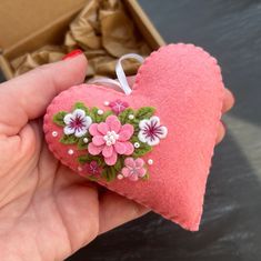 a hand holding a pink heart with flowers on it