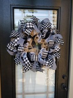 a black and white wreath hanging on the front door with ribbon around it's edges