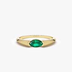 a gold ring with an oval green stone on the front and side, set against a white background