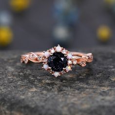 a close up of a ring on a rock with flowers in the middle and an oval shaped blue stone surrounded by smaller white stones