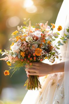 a bride holding a bouquet of flowers in her hand with the sun shining on her