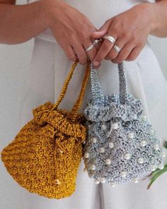 two crocheted purses with pearls on the handles, one yellow and one blue