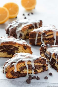 several pieces of cake with icing and chocolate chips around it on a white surface