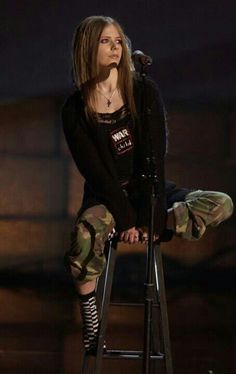 a woman sitting on top of a stool next to a microphone