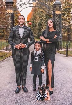 a man, woman and child standing in front of an iron gate