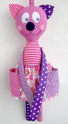 a stuffed animal hanging on the wall with polka dots and pink stripes, in front of a white wall