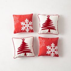 four red and white christmas pillows with snowflakes on the bottom one has a tree