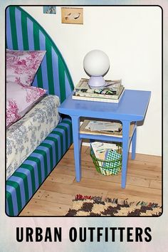 a blue table with books on it next to a bed