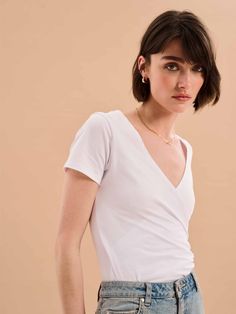 Sustainable essentials. Crafted from 100% BCI organic cotton, the Hilary top features a faux wrap detail and subtle ruching to flatter every form. Whether you dress it up or down, this elevated basic is a timeless style that works with any look. Versatile Fitted Short Sleeve Wrap Top, Versatile Fitted Wrap Top With Short Sleeves, Fitted Cotton V-neck Wrap Top, Fitted Solid Color Top With Twist Front, Fitted Twist Front Top, Fitted Solid Top With Surplice Neckline, Versatile Cotton Wrap Tops, Fitted Cotton Wrap Top Casual, Jersey Top