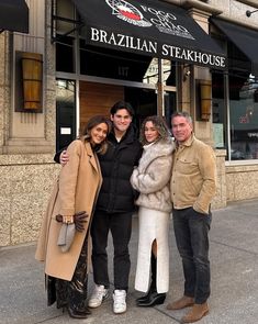 four people standing in front of a restaurant