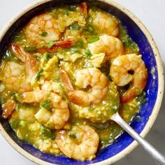 a blue bowl filled with shrimp and green sauce on top of a white countertop