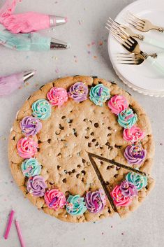 a cookie cake decorated with colorful frosting and sprinkles on a table