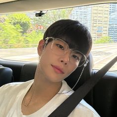 a young man wearing glasses sitting in the back seat of a car