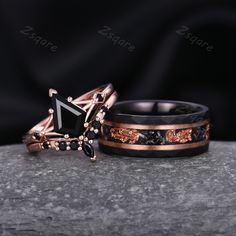 two wedding bands with black diamonds and rose gold inlays, on top of a rock