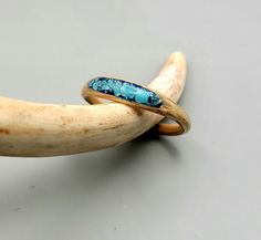 two gold rings with blue stones sitting on top of a wooden banana peel, against a gray background